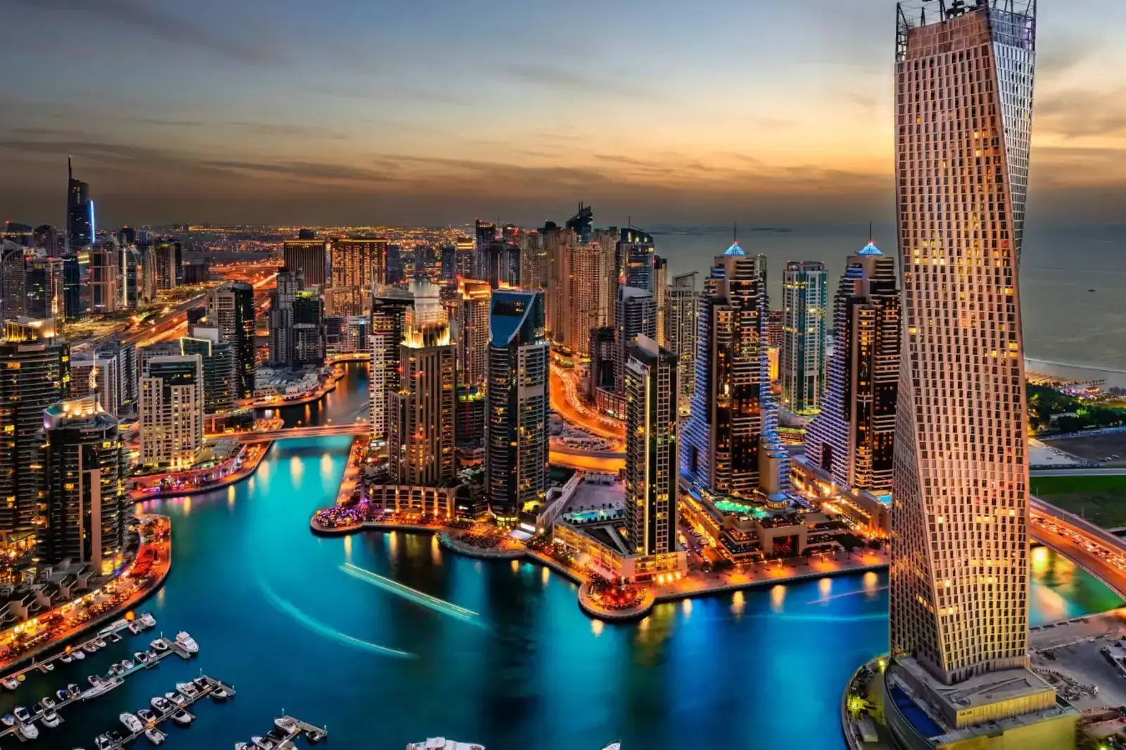 Panoramă modernă Dubai Marina la apus, zg&acirc;rie-nori iluminați și iahturi pe canal.