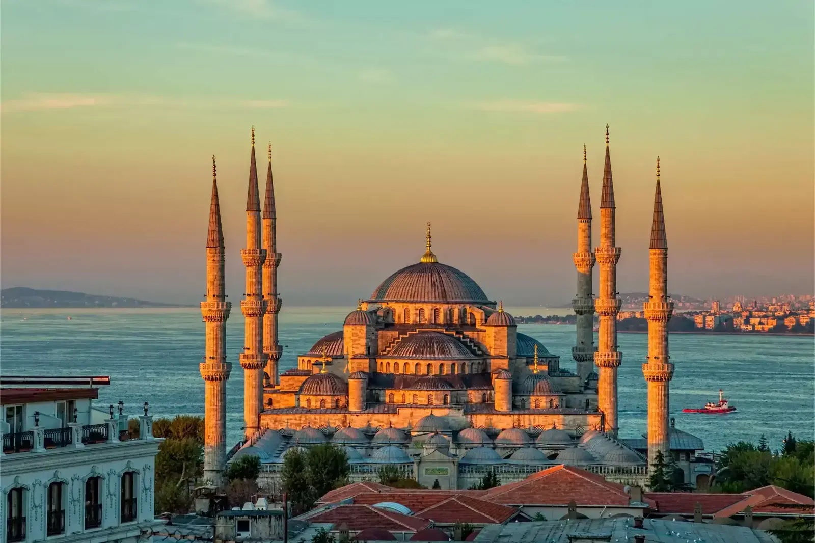 Moscheea Albastră din Istanbul la apus, cu minarete și vedere spre Bosfor.