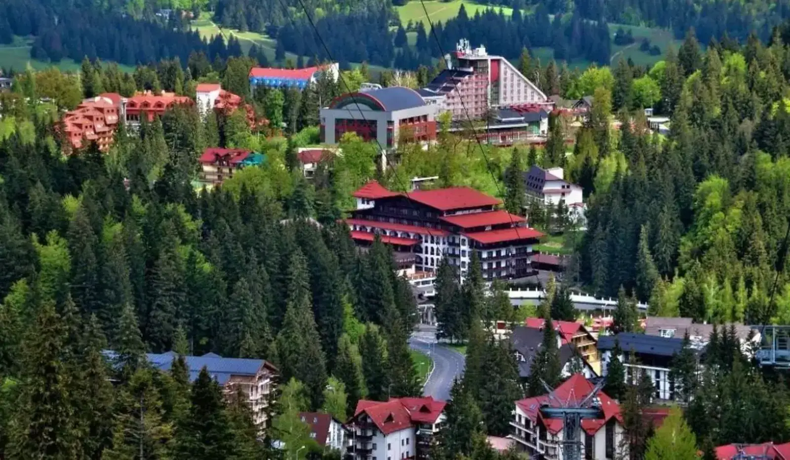 Poiana Brașov, stațiune montană &icirc;nconjurată de păduri și hoteluri.